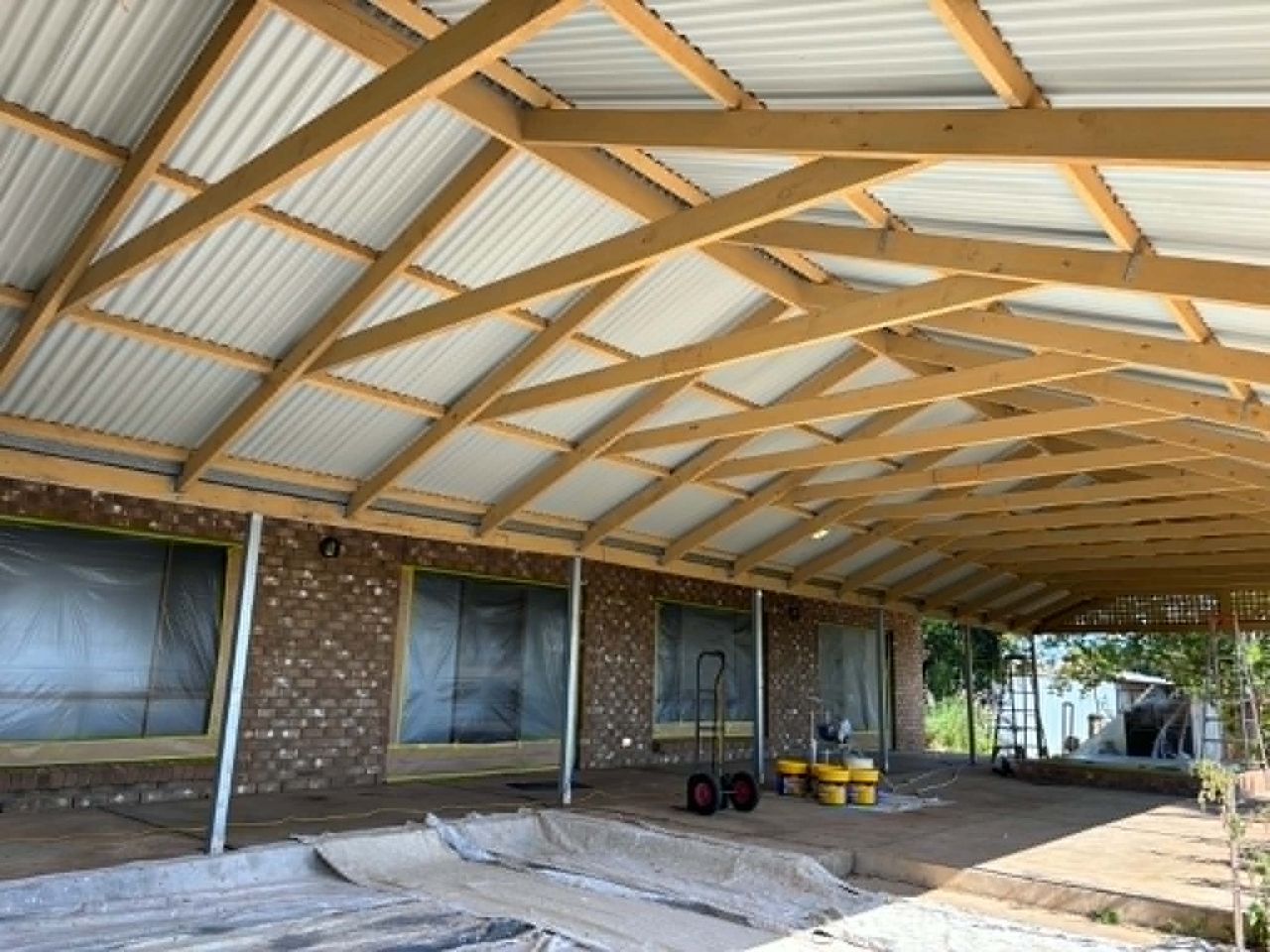 Covered patio before painting, bare timber and brick